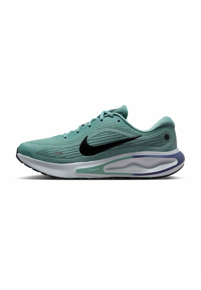 Zielony sportowy sneaker z teksturowaną siateczką, czarnym logo w kształcie łyżwy, amortyzowaną podeszwą w białym kolorze z purpurowymi akcentami oraz systemem sznurowania.
