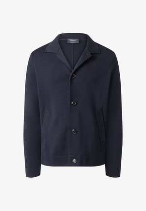 Merinovillaneule neulejakku, jossa on kaulus, viisi nappia edessä ja kaksi sivutaskua. Sileä pinta ja rento istuvuus.