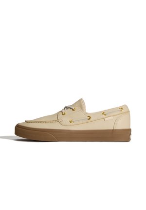 Beżowe skórzane buty typu boat z brązową gumową podeszwą, złotymi przelotkami, białymi sznurówkami i przeszyciami w stylu mokasynów.