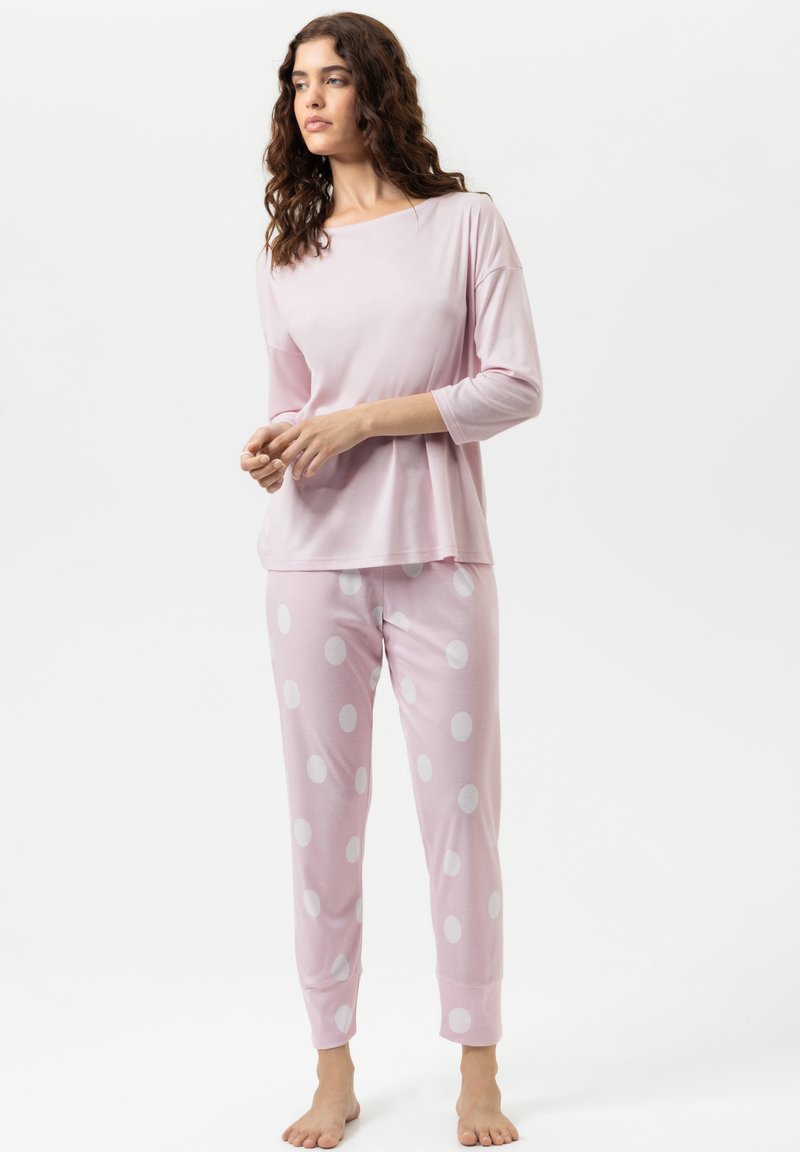Ensemble de pyjama rose clair, comprenant un haut à manches longues et un pantalon fuselé à pois blancs. Tissu doux avec une coupe décontractée.