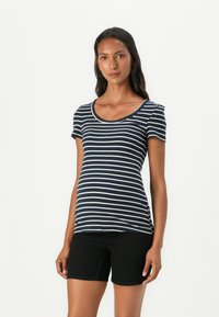 Μπλούζα με ρίγες ναυτικού σε κοντό μανίκι και στρογγυλή λαιμόκοψη, φτιαγμένη από ραμμένο ύφασμα. Συνδυασμένη με μαύρες βερμούδες, αναδεικνύει μια εφαρμοστή σιλουέτα.