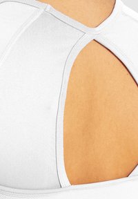 Weißer Sport-BH mit einem Ausschnitt-Design auf dem Rücken, gerippten Textur und verstärkten Nähten entlang des Halsausschnitts und der Armausschnitte.