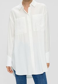 White long-sleeve button-up shirt with two chest pockets, made of lightweight fabric. Features a collared neckline and a curved hem.