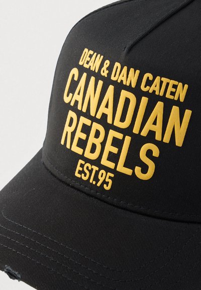 Čierna baseballová čiapka s vyšším výrazným žltým textom "DEAN & DAN CATEN CANADIAN REBELS EST.95", s tvarovanou korunou a zakriveným šiltom.