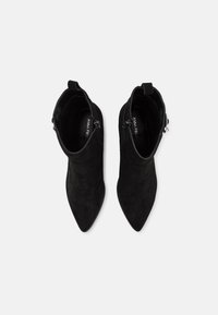Černé semišové kotníkové boty s špičatou špičkou, zapínáním na zip a hladkým povrchem, s mírným podpatkem a bez viditelného kování.