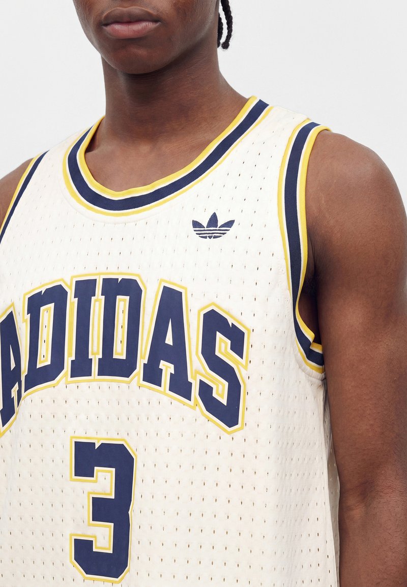 Close-up of person wearing white Adidas basketball jersey with navy and yellow trim and number three on front.
