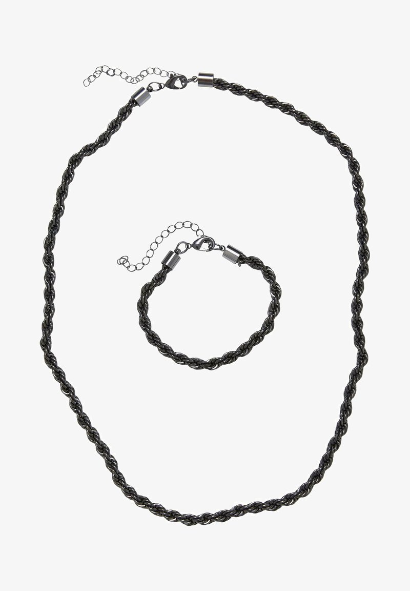 Conjunto de collar y pulsera trenzados en negro, con un diseño retorcido que incluye broches metálicos y una cadena ajustable para variar el tamaño.