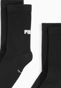 Czarne bawełniane skarpetki typu crew o prążkowanej strukturze, z białym nadrukowanym logo z boku oraz małym białym tekstem na palcach.