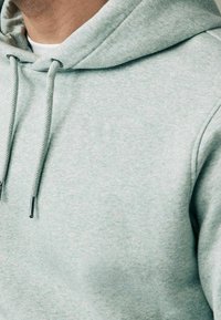 Lichtgroene hoodie gemaakt van zacht materiaal. Voorzien van een capuchon met trekkoord en metalen uiteinden, met een gestructureerd patroon en een ontspannen pasvorm.