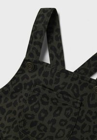 Dunkelgrüne Corduroy-Latzhose mit schwarzem Leopardenmuster, ausgestattet mit verstellbaren Trägern, einer Tasche und Metallakzenten.