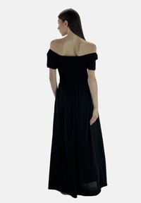 Sort off-shoulder maxi kjole med rynket bust, korte ærmer og svajende nederdel. Glat stofoverflade, designet til en afslappet pasform.