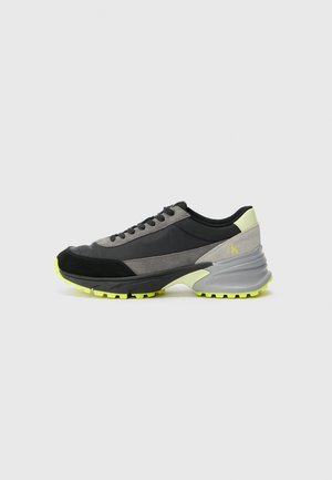 Sneaker con un design nero, grigio e verde neon. Realizzato in suede e materiali sintetici con una suola texturizzata e un colletto imbottito.