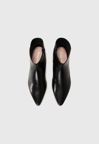 Bottines en cuir noir avec un bout pointu, texture lisse, fermeture éclair sur le côté et une semelle intérieure rose douce. Vue de dessus sans lacets.