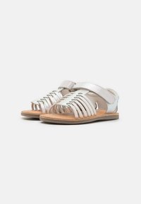 Sandalias plateadas con un diseño de tiras, que cuentan con una suela plana y una correa ajustable de gancho y bucle. Parte superior de cuero texturizado con detalles recortados.