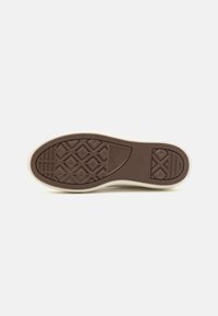 Semelle de chaussure en caoutchouc marron avec des motifs texturés, incluant des formes en diamant et des lignes horizontales. Détails en blanc autour de la semelle.