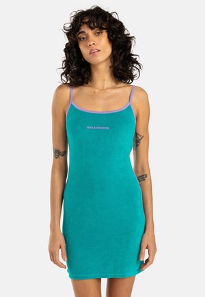 A sleeveless teal dress with a fitted shape, purple trim, and a small logo in the center. Made from soft, breathable fabric.