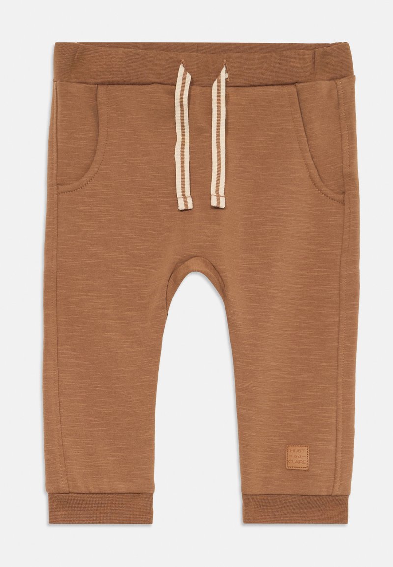 Brune bomull joggebukser med snor i midjen, sidelommene, ribbede mansjetter, og en liten etikett på leggen.