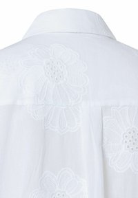 Witte blouse met bloemendiscriminatie in verhoogde textuur, een standaardkraag en een rechte rugdesign.