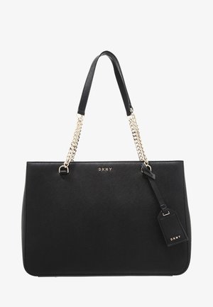 Sac fourre-tout en cuir noir de DKNY avec chaîne en or et lanières en cuir, comportant une étiquette de marque suspendue à la poignée.