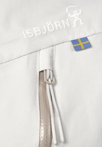 Hvidt stof med Isbjörn-logo, sølv lynlås, og et lille svenske flagmærke. Har en glat tekstur og et rent design.