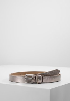 Ceinture en cuir métallisé argent roulée avec boucle rectangulaire argentée reposant sur une surface blanche avec un fond uni.