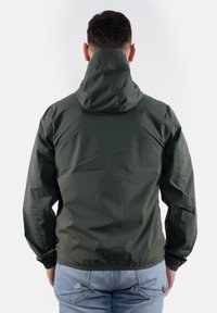 Giacca impermeabile verde scuro con cappuccio, polsini elasticizzati e taglio dritto, che mostra una superficie liscia e testurizzata. Dettagli di cucitura visibili.