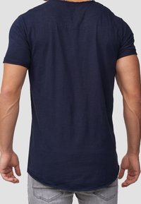 T-shirt blu navy a maniche corte con orlo arrotondato e texture morbida, che presenta un design semplice e dettagli di cucitura minimal.