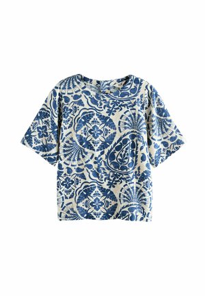 Top a maniche corte con base color crema e motivi floreali e geometrici blu. Presenta una scollatura rotonda e una vestibilità rilassata.