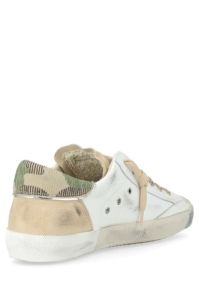 Baskets blanches et beiges avec un talon en tissu camouflage, lacets beiges et semelle en caoutchouc usée, vues sous un angle arrière.