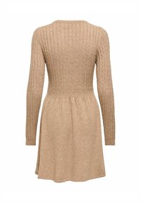 Stickad klänning i ljus beige med ribbad textur. Långa ärmar, figurnära midja och utsvängd kjol. Enkel rund halsringning, inga utsmyckningar.
