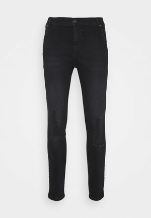 Jeans de mezclilla negra con un ajuste slim, que presentan parches desgastados en la parte frontal, cierre de botón y diseño estándar de cinco bolsillos.
