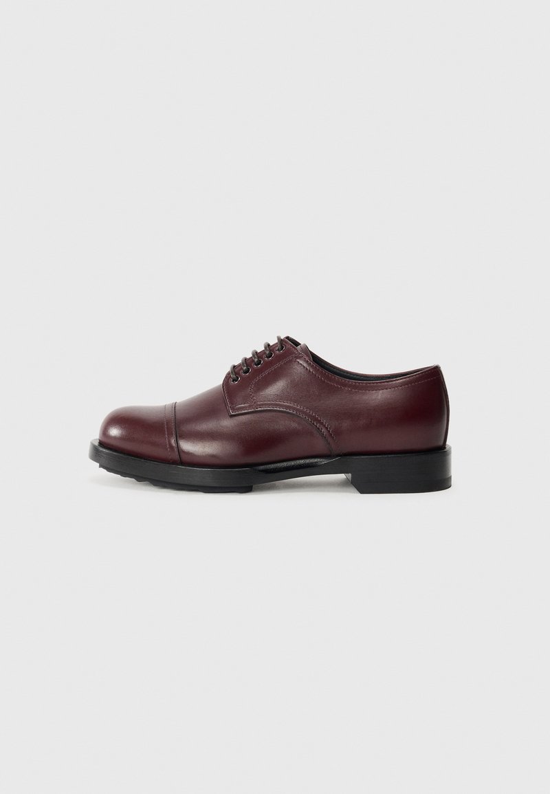 Scarpe da uomo in pelle bordeaux con punta arrotondata e design a punta a cappuccio. Suola nera con tacco basso e cinque asole parallele per i lacci.