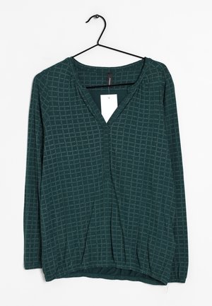 Blusa verde de manga larga con cuello en V, confeccionada en una tela suave con un patrón de cuadrícula y dobladillo elástico. Etiqueta adherida en el cuello.