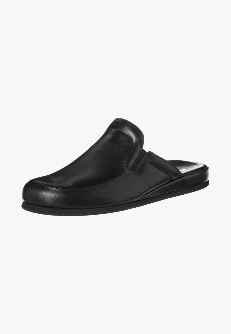 Black leather slip-on shoe with a rounded toe, stitched detailing, and a flat rubber sole. Features minimalistic design and soft texture.