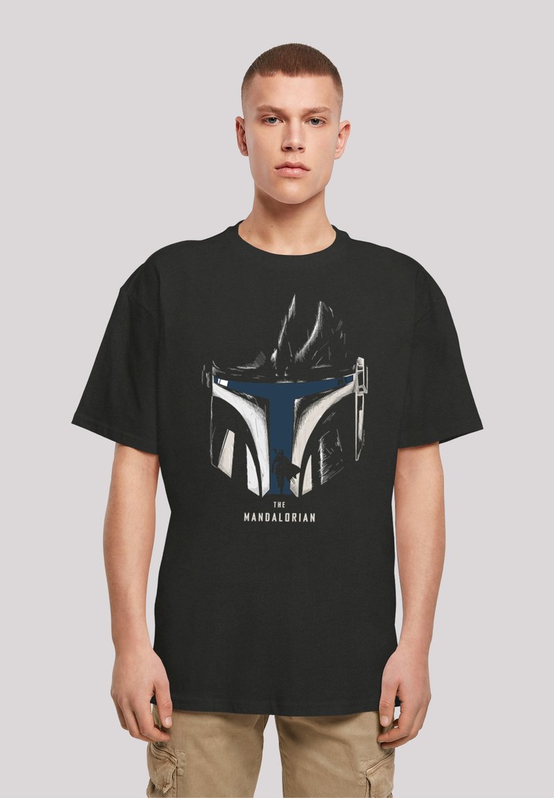 Svart t-skjorte med grafikk av et hjelm, med blå og hvite detaljer og teksten "THE MANDALORIAN" under.