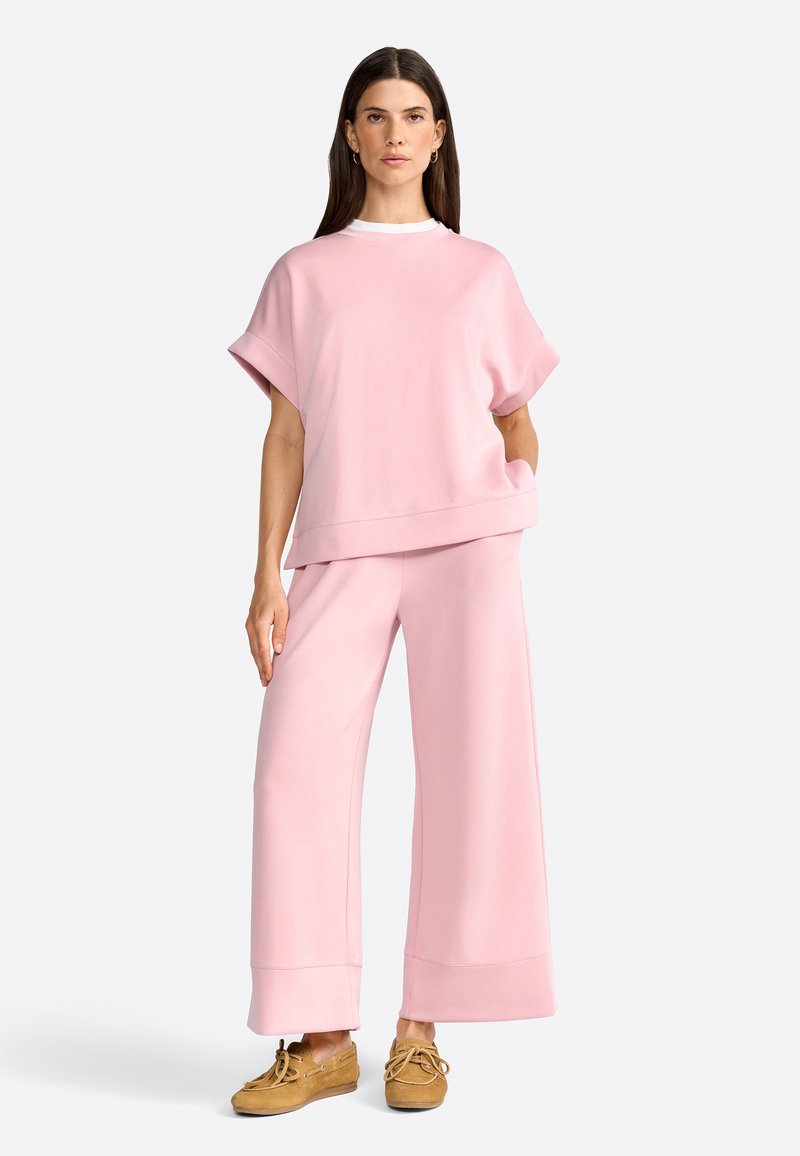Pink oversized sweatshirt and wide-leg pants made from soft fabric. Sweatshirt has a crew neckline; pants feature a wide hem and relaxed fit.
