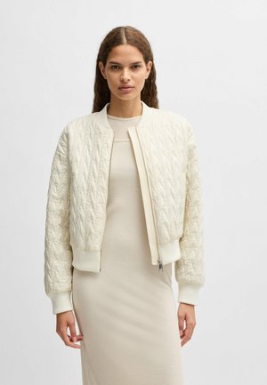 Quilted cream bomber jacket with ribbed cuffs and hem, featuring a front zip closure and a smooth, satin-like texture.