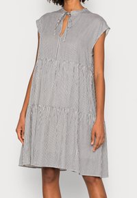 Zwart-wit gestreepte jurk met een ronde kraag, korte cap sleeves en een striksluiting bij de hals, met een tiered rok ontwerp.