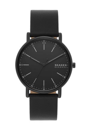 Schwarze minimalistische Armbanduhr mit Lederarmband, rundem Zifferblatt, weißen Markierungen, drei Zeigern und "Skagen Denmark" Branding auf dem Zifferblatt.