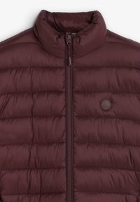 Chaqueta acolchada burdeos con cuello alto, costuras horizontales, cremallera frontal y un parche redondo con un logo que presenta una calavera y huesos cruzados.