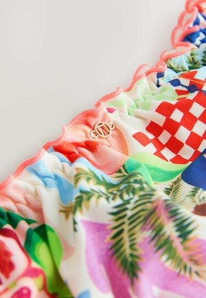 Haut de maillot de bain multicolore à volants présentant des motifs floraux et géométriques vibrants, avec un bord festonné et un détail de fermoir logo doré.