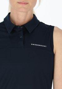 Polo senza maniche di colore navy con colletto, caratterizzato da un tessuto testurizzato e un logo bianco "SWEDEMOUNT" sulla parte sinistra del petto.
