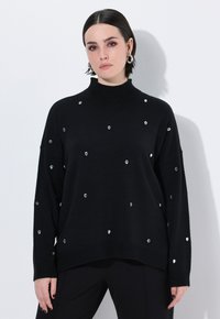 Maglione nero a maglia con collo alto, caratterizzato da paillettes trasparenti sparse. Vestibilità ampia con polsini e orlo a costine, texture liscia.