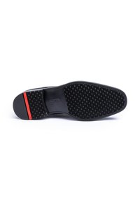Schwarze Schuhsohle mit strukturiertem Oberflächen, versehen mit einem roten Akzentstreifen an der Ferse. Das Design umfasst eine flache, breite Form für Stabilität.