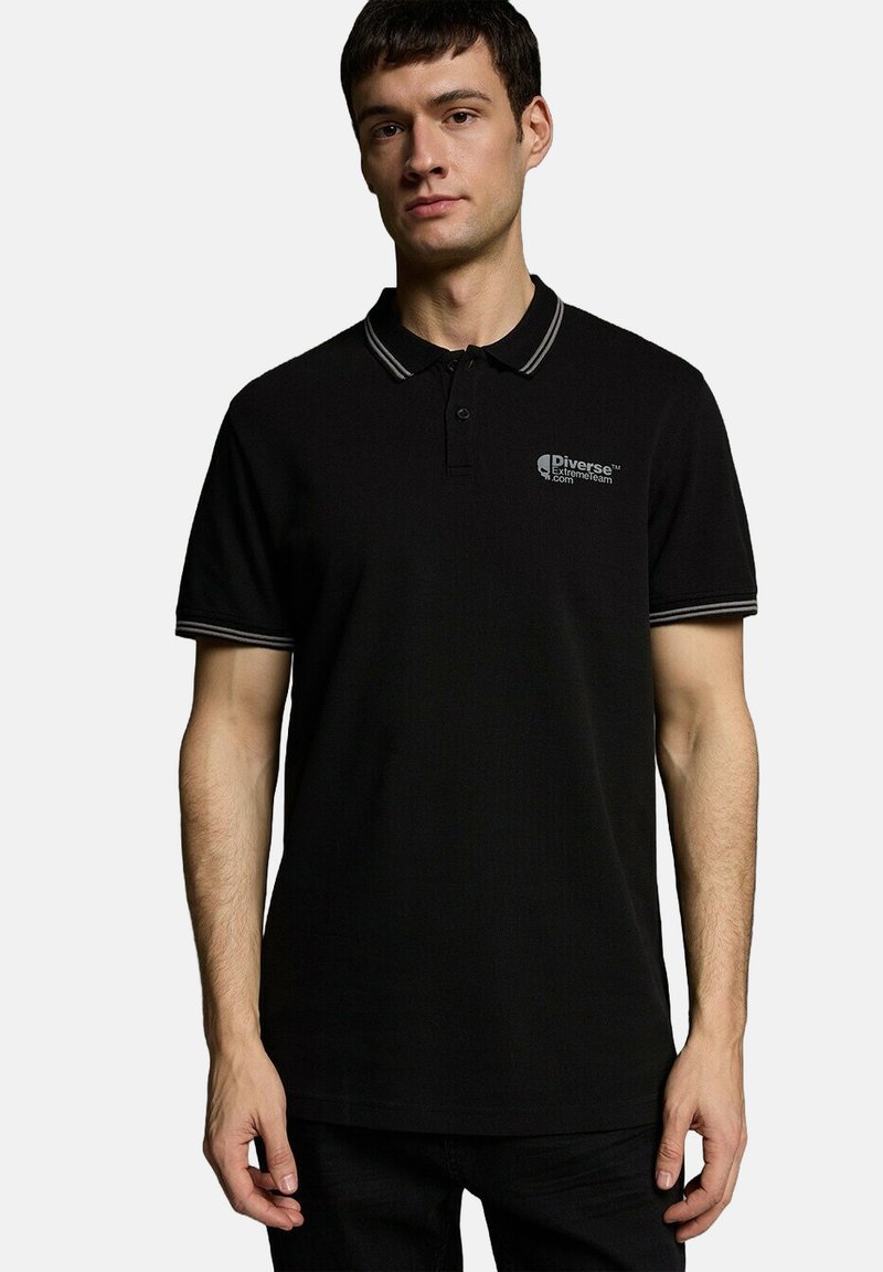 Czarna koszulka polo z kołnierzykiem i srebrnymi akcentami. Posiada małe logo na klatce piersiowej. Wykonana z miękkiego, teksturowanego materiału.