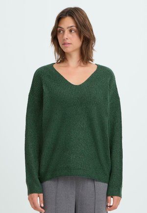 Pull en tricot vert avec décolleté en V, coupe ample, épaules tombantes et texture côtelée. Tissu doux avec manches longues et fentes sur les côtés.