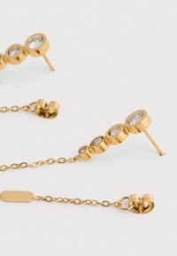 Χρυσά σκουλαρίκια με σχέδιο αλυσίδας, που διαθέτουν τέσσερις διαυγείς πολύτιμες πέτρες σε στρογγυλή κοπή, με αυξανόμενο μέγεθος σε κάθετη σειρά.