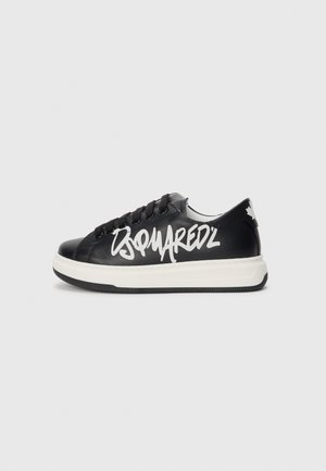Zapatilla de cuero negra con un logotipo de estilo graffiti en blanco, cordones planos, cuello acolchado y suela de goma con una entresuela blanca contrastante.