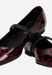 Ballerines à imprimé léopard rouge et noir, avec un petit talon, dotées d'une bride noire texturée sur le cou-de-pied et d'une finition brillante.