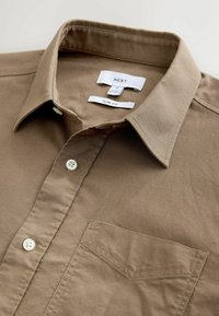 Cămașă slim fit, maro deschis, cu guler button-down, buzunar pe piept și nasturi albi; realizată dintr-un material neted, texturat.
